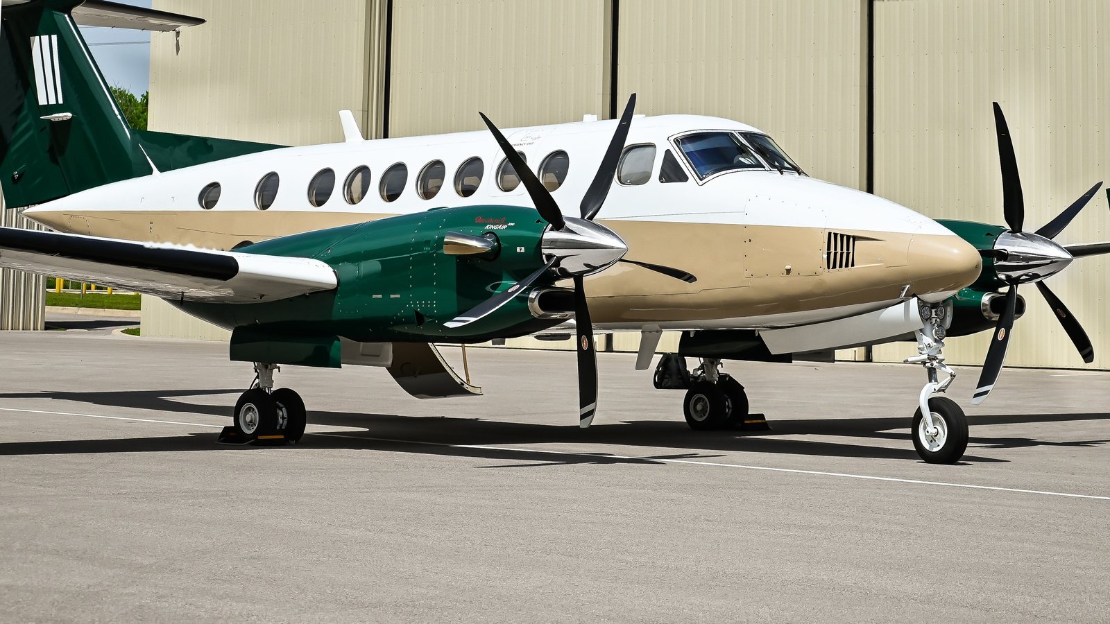 King Air 350 in green and tan livery outside a hangar